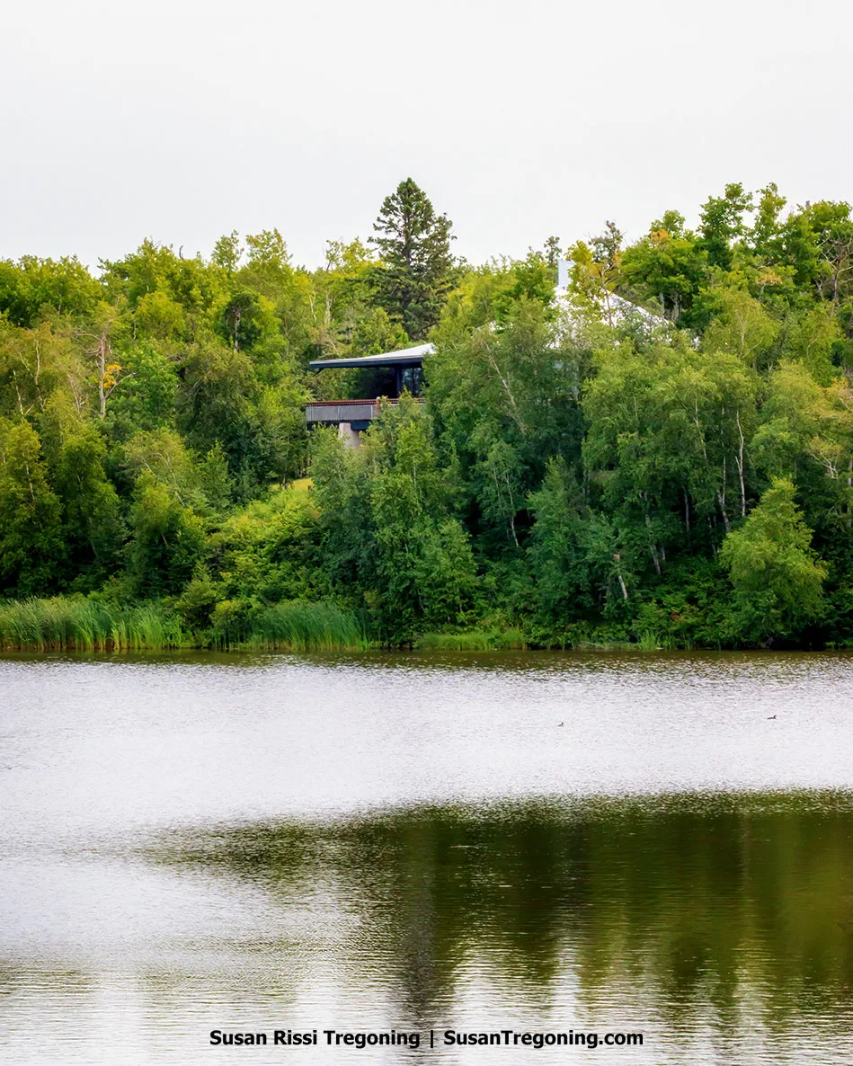 Willis Pavilion overlooking Lake Stormon, its modern structure framed by dense forest with the calm water reflecting the trees.