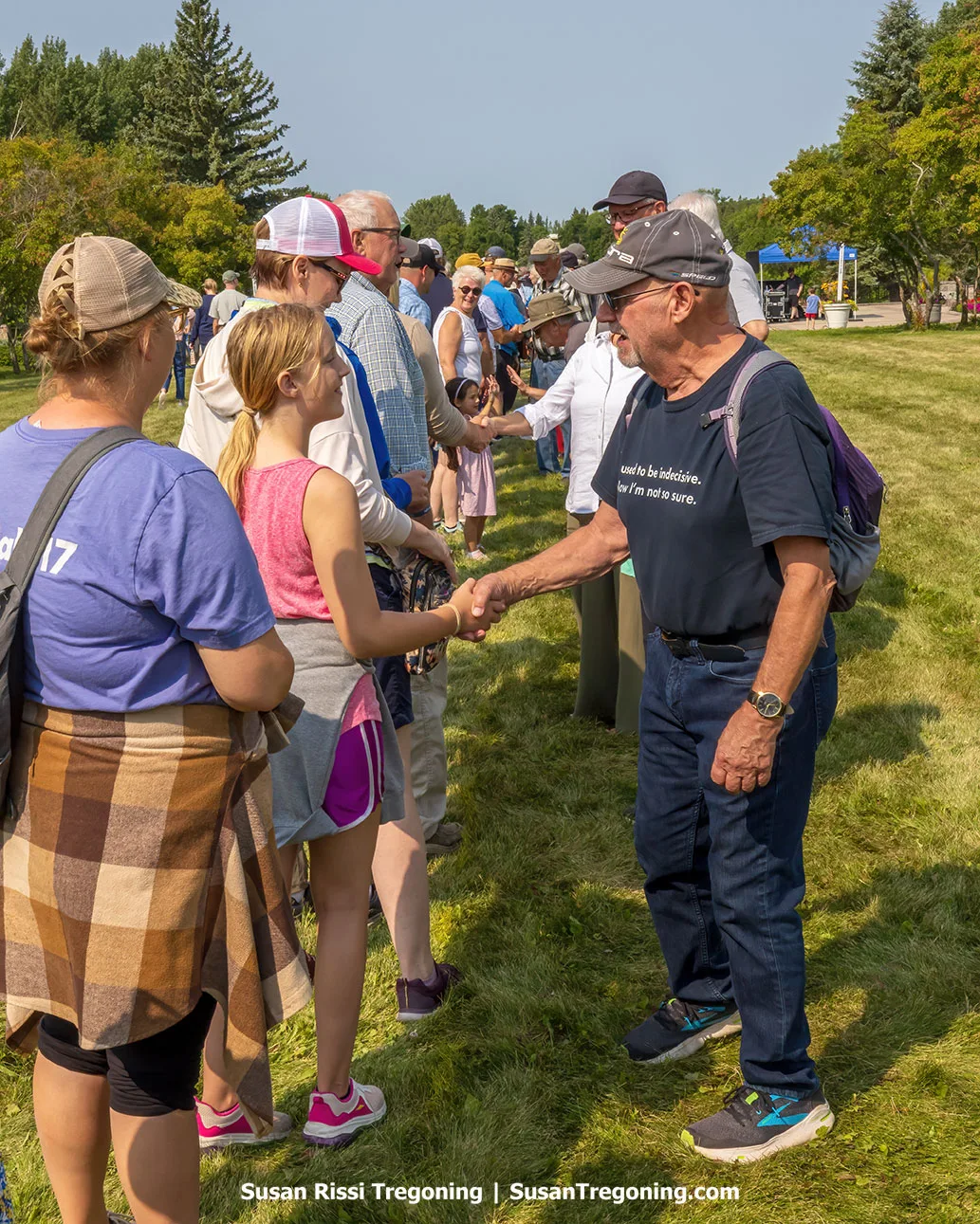 Visitors from the United States and Canada reach across the grassy border at the International Peace Garden, shaking hands during the Handshake Across the Border event.