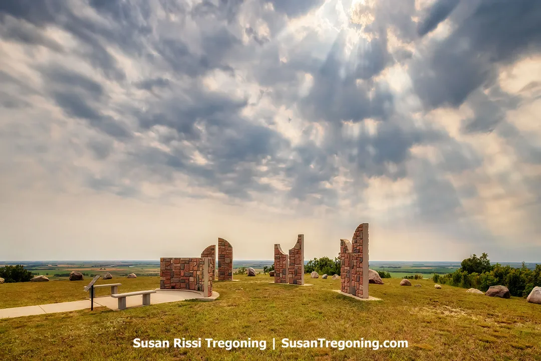 Mystical Horizons astronomical site near Bottineau, North Dakota, featuring its concrete solstice and equinox alignment structures set atop the Turtle Mountain Scenic Byway. Built in the early 2000s as a modern interpretation of ancient observatories, the site was envisioned by aerospace engineer Jack Olson to blend science, art, and landscape. The image shows the hillside overlook and the sculptural markers pointing toward celestial events, with wide prairie views stretching beyond the ridge.